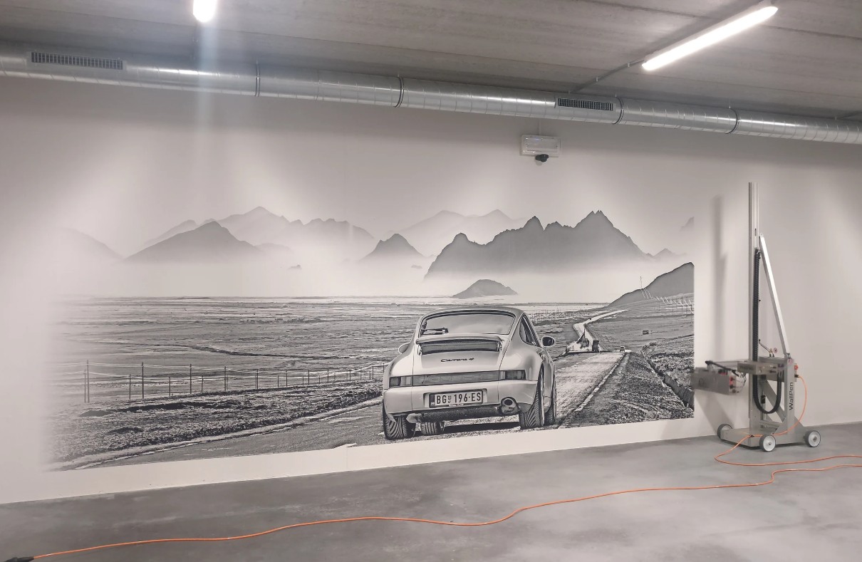 Fresque murale noir et blanc d'une Porsche sur une route de montagne dans un garage